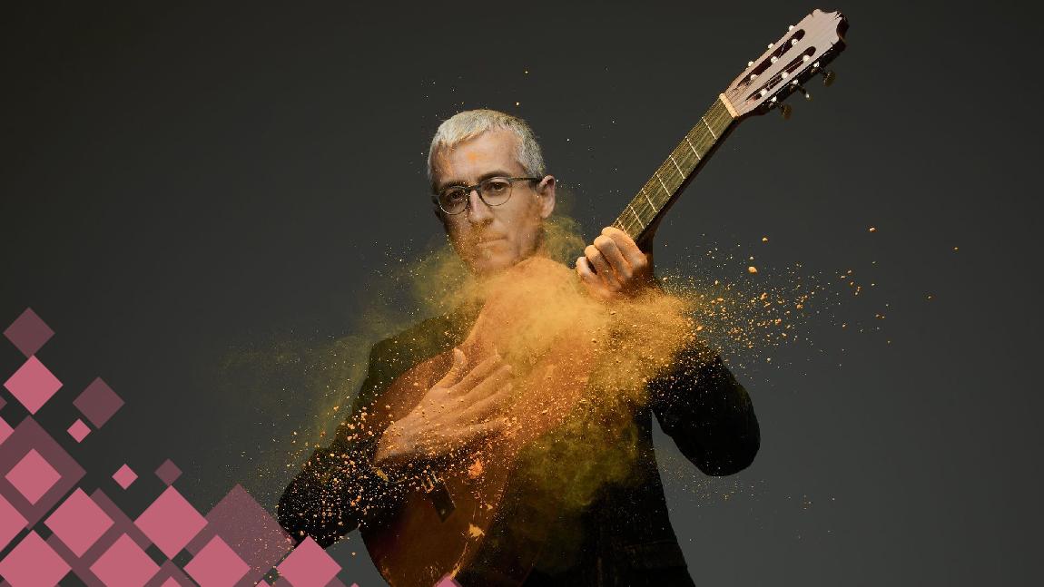 Quentin Dujardin tient une guitare en main de laquelle s'échappe de la poussière orange.