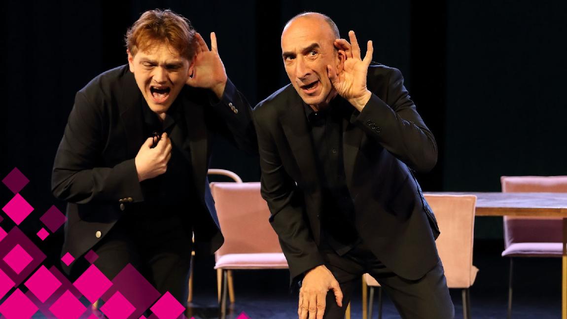 Deux comédiens sur scène tendent l'oreille pour mieux entendre.