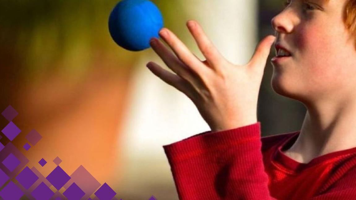 Un enfant jongle avec des balles bleues.