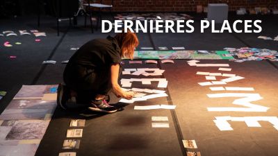 Une femme accroupie sur une scène trie des photos qui jonchent le sol.